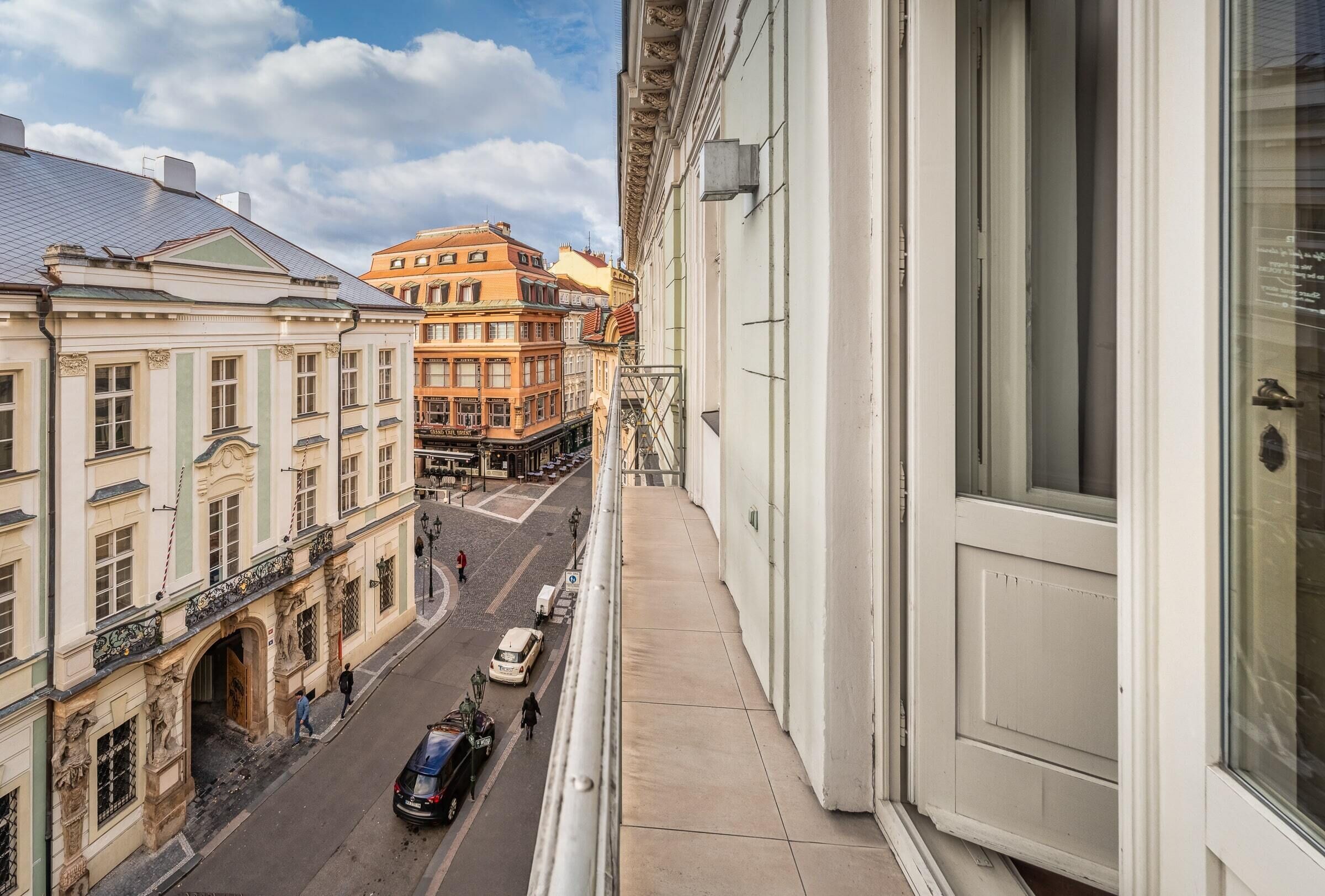 Un balcón con vista a una calle, edificios y cielo despejado.