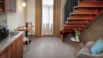 Um espaço compacto com cozinha compacta, área de jantar, sofá e escada.