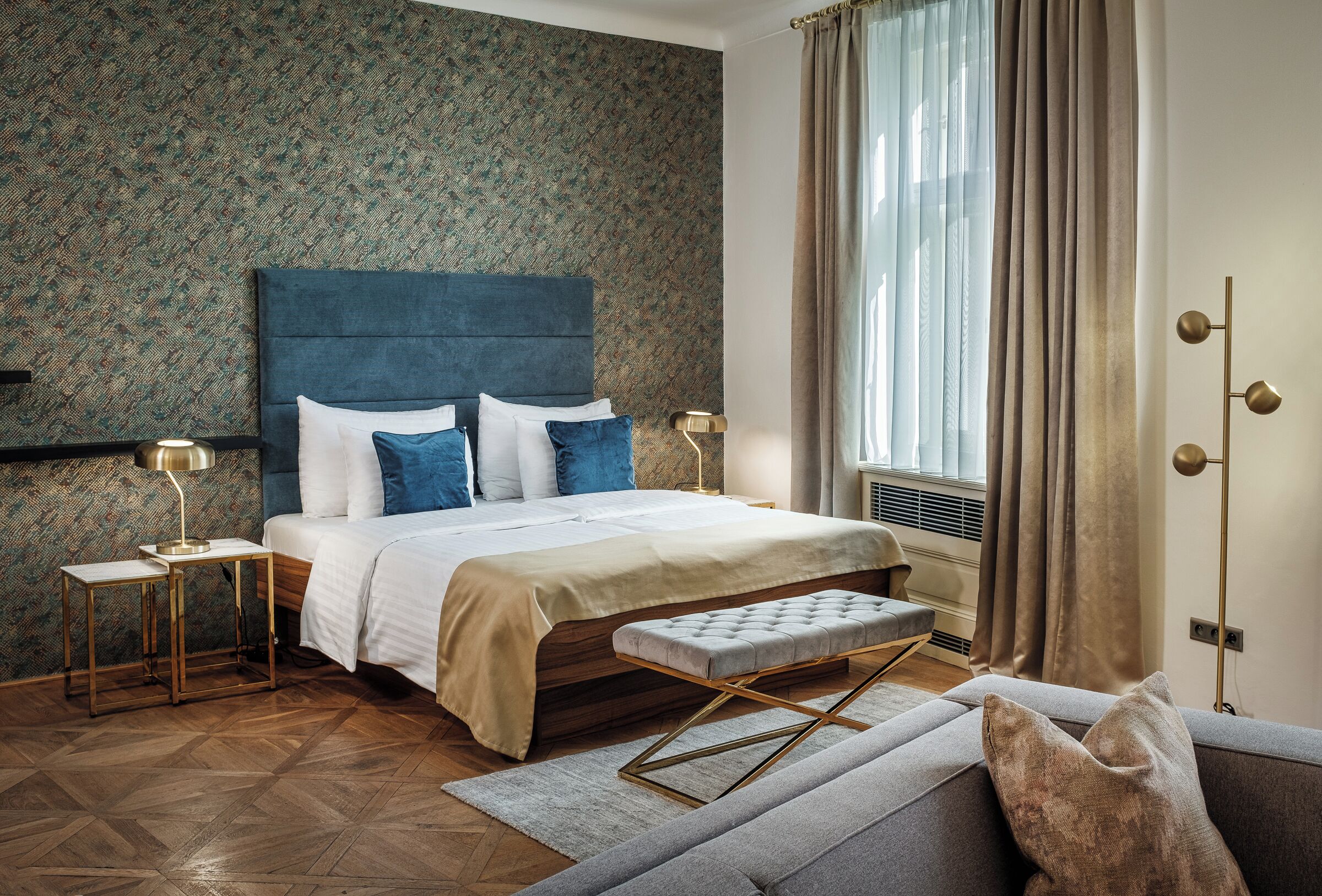 A modern bedroom with a large bed, a bench, and a sofa.