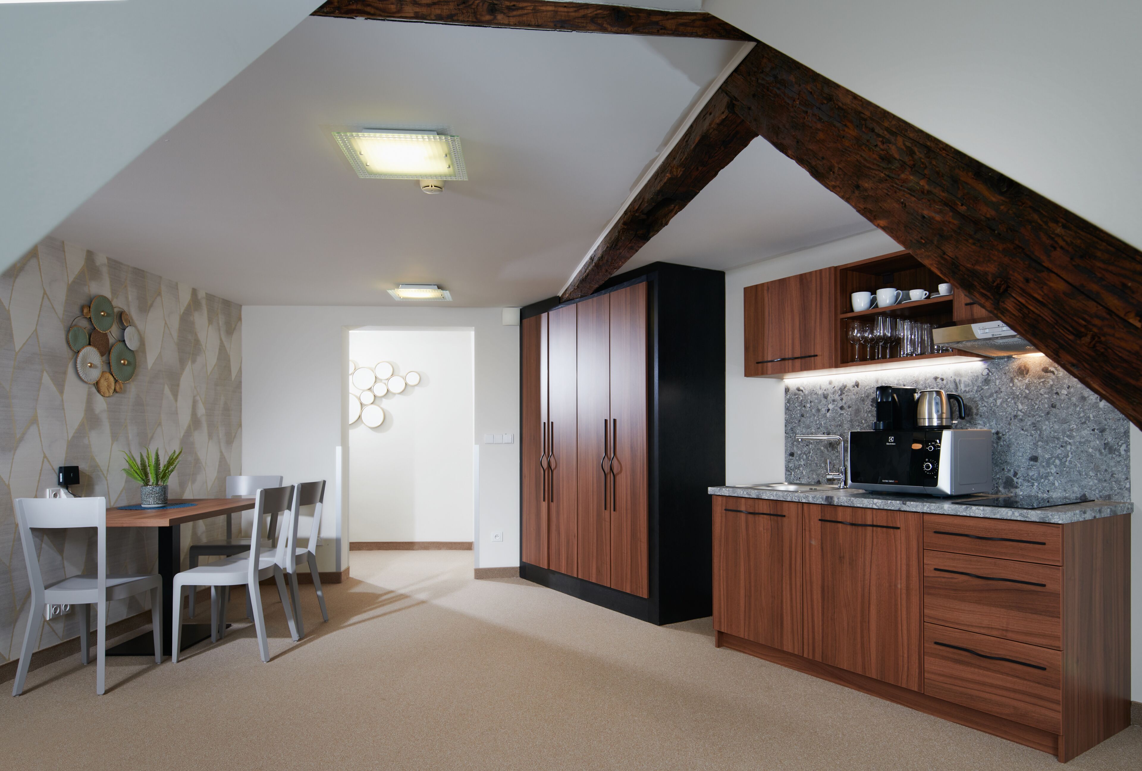 Eine moderne Küche mit Holzschränken, einer Kaffeemaschine und einem Essbereich mit Tisch und Stühlen.