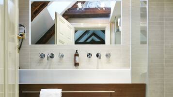 Une salle de bain moderne avec un grand miroir, une poutre en bois au plafond et une baignoire.