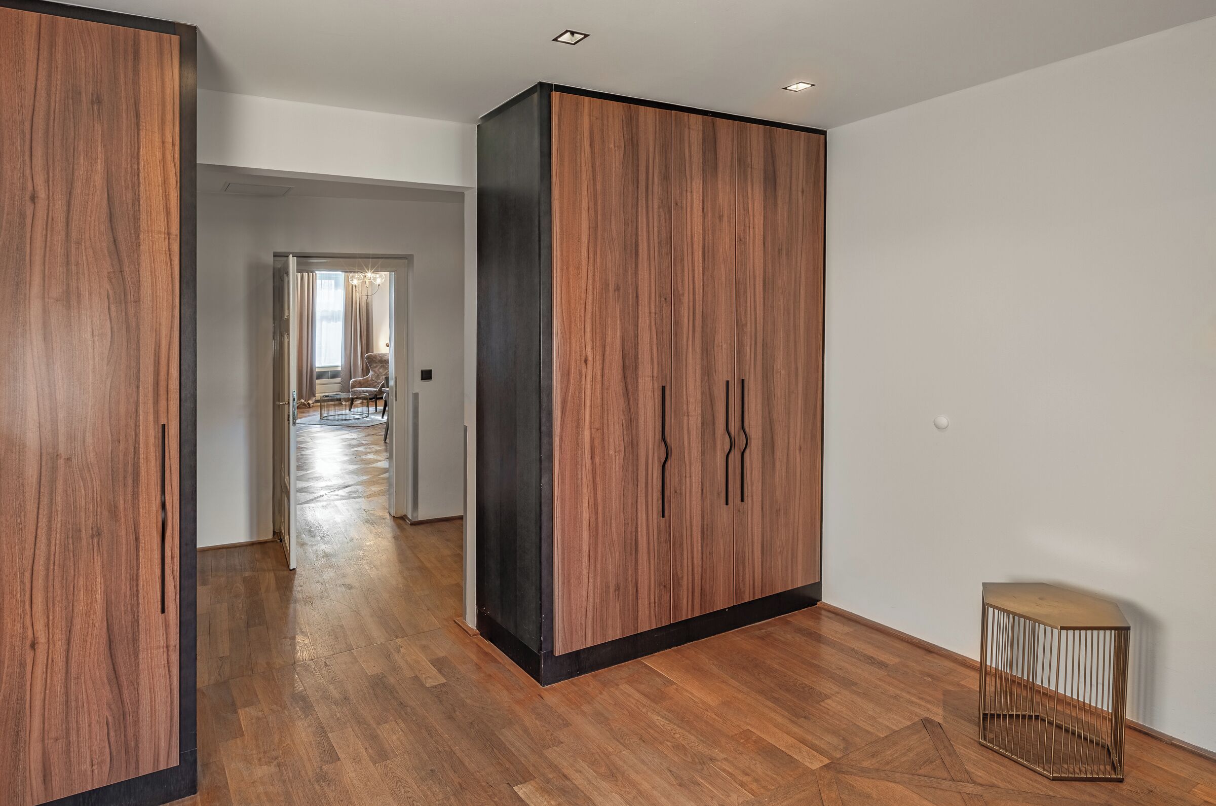 A modern interior with a wooden floor, a large wardrobe, and a small side table.
