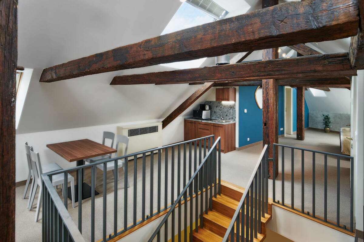 A loft-style room with a dining area, kitchen, and a staircase leading to an upper level.