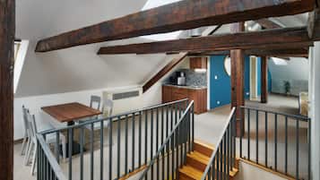 Habitación estilo loft con comedor, cocina y una escalera que lleva a un nivel superior.