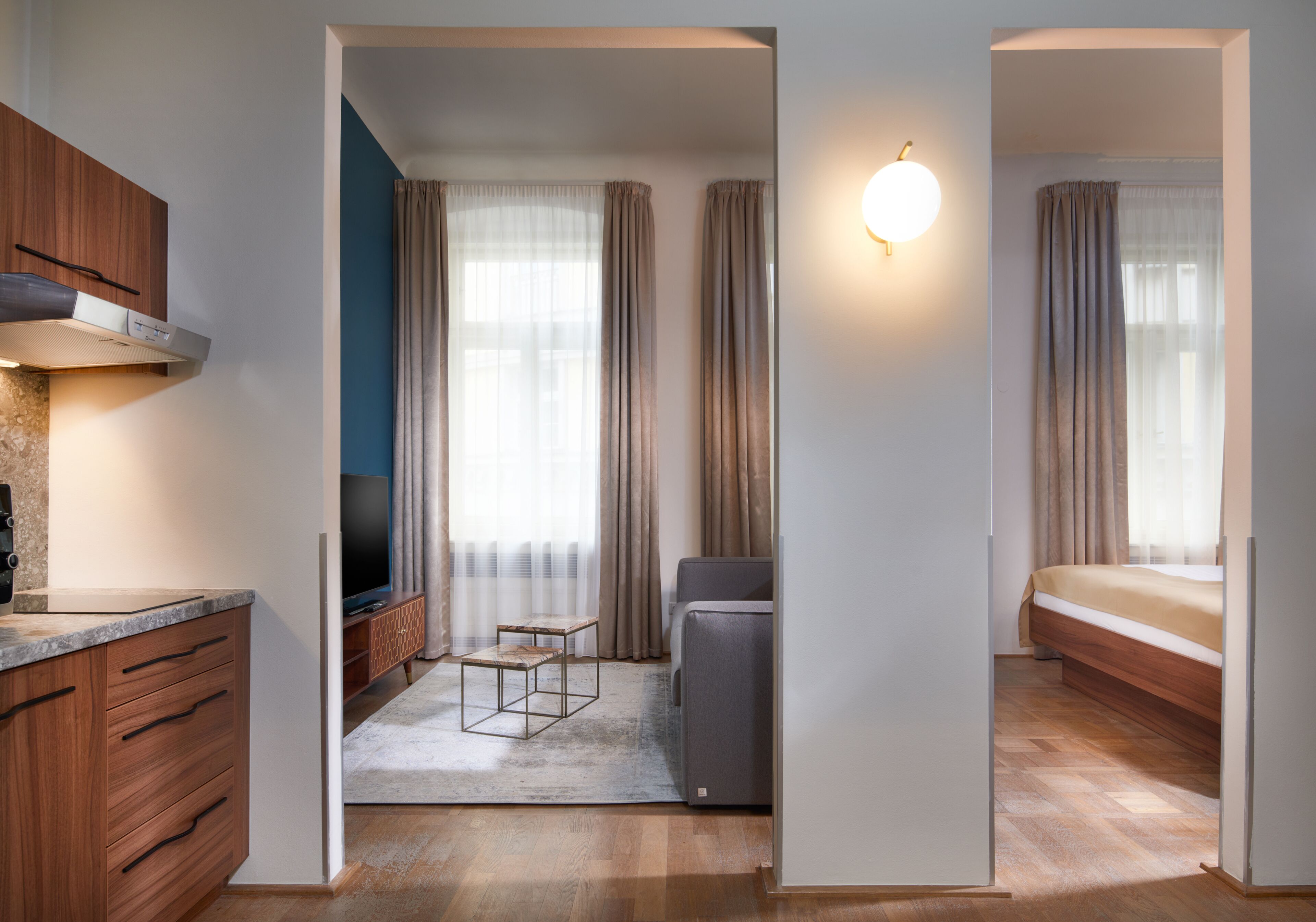 A modern hotel room with a wooden cabinet, a flat-screen TV, a sofa, and a bed.