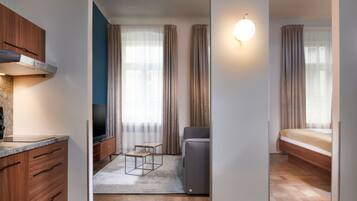 A modern hotel room with a wooden cabinet, a flat-screen TV, a sofa, and a bed.