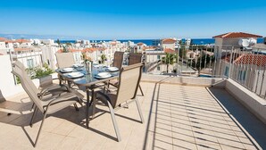 A terrace with a table set for dining, overlooking a coastal cityscape. - Protaras holiday villa - rentprivatevillas 045 (Protaras)