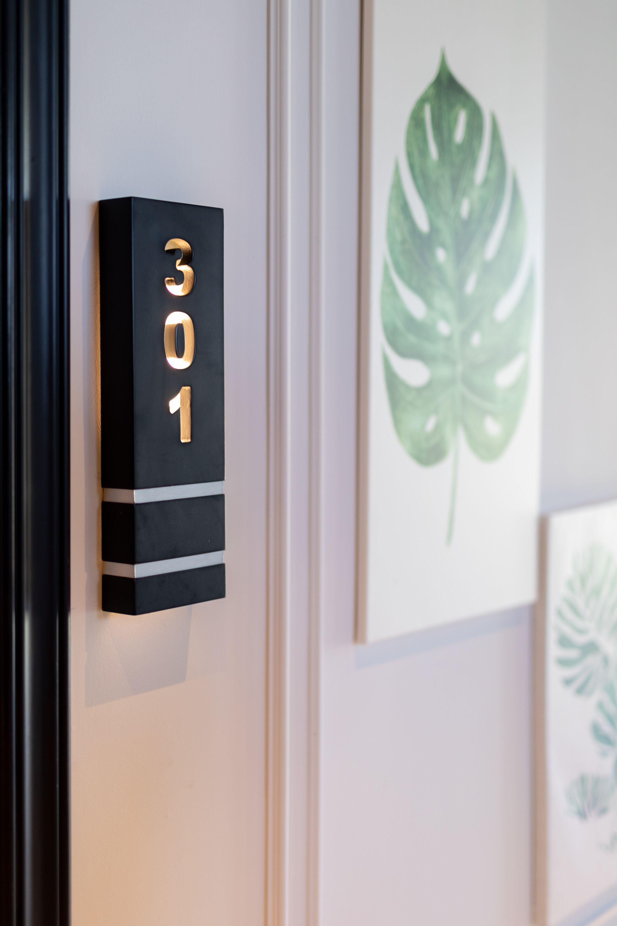 A black wall-mounted sign with the numbers "301" in gold, indicating a room number.