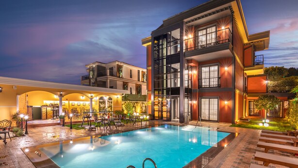 Un hôtel moderne doté d’une piscine, d’un espace extérieur aménagé et de balcons bien éclairés.