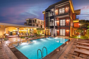 Un hôtel moderne doté d’une piscine, d’un espace extérieur aménagé et de balcons bien éclairés.