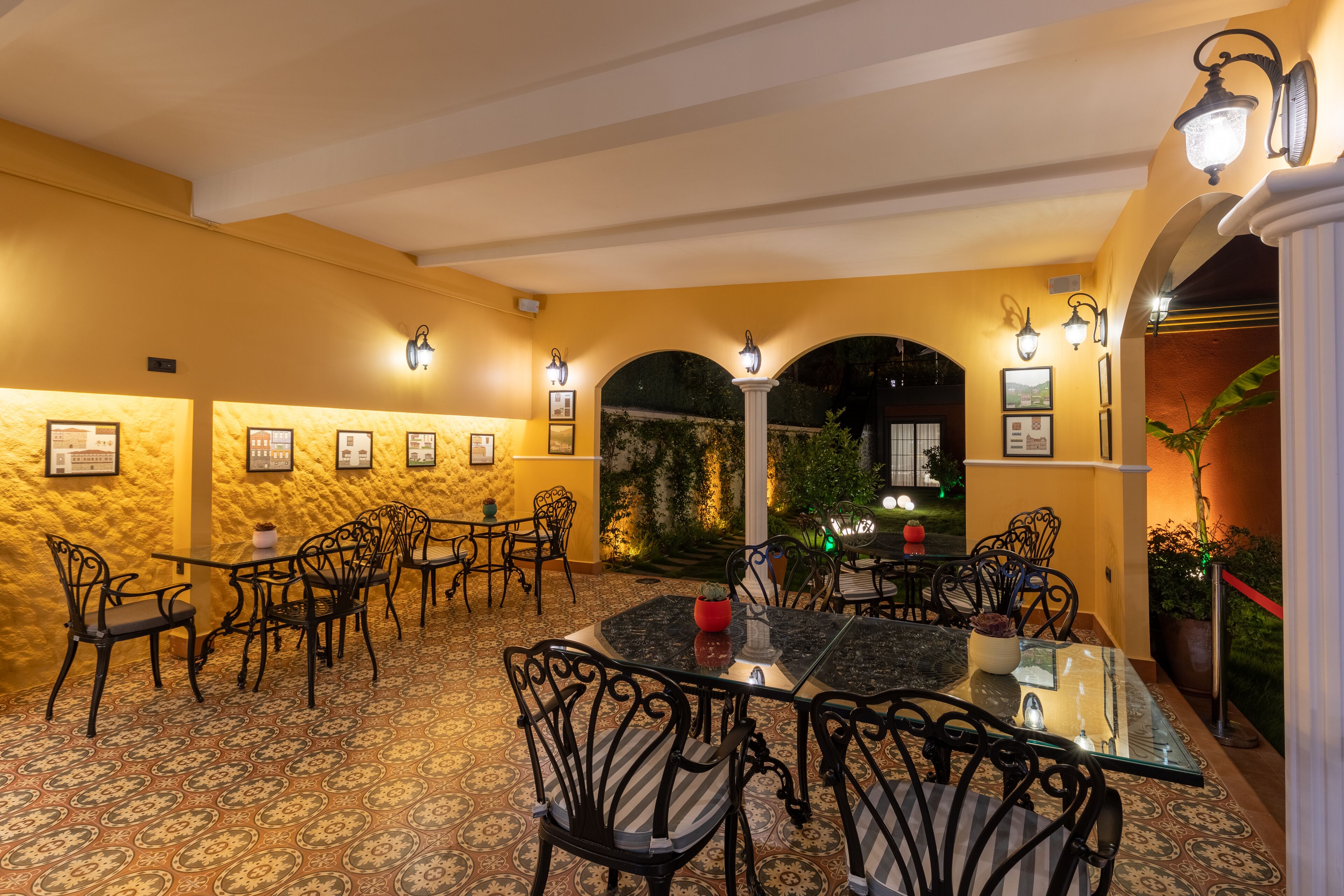 A dining area with tables and chairs, framed pictures on the walls, and a view of the outdoors.