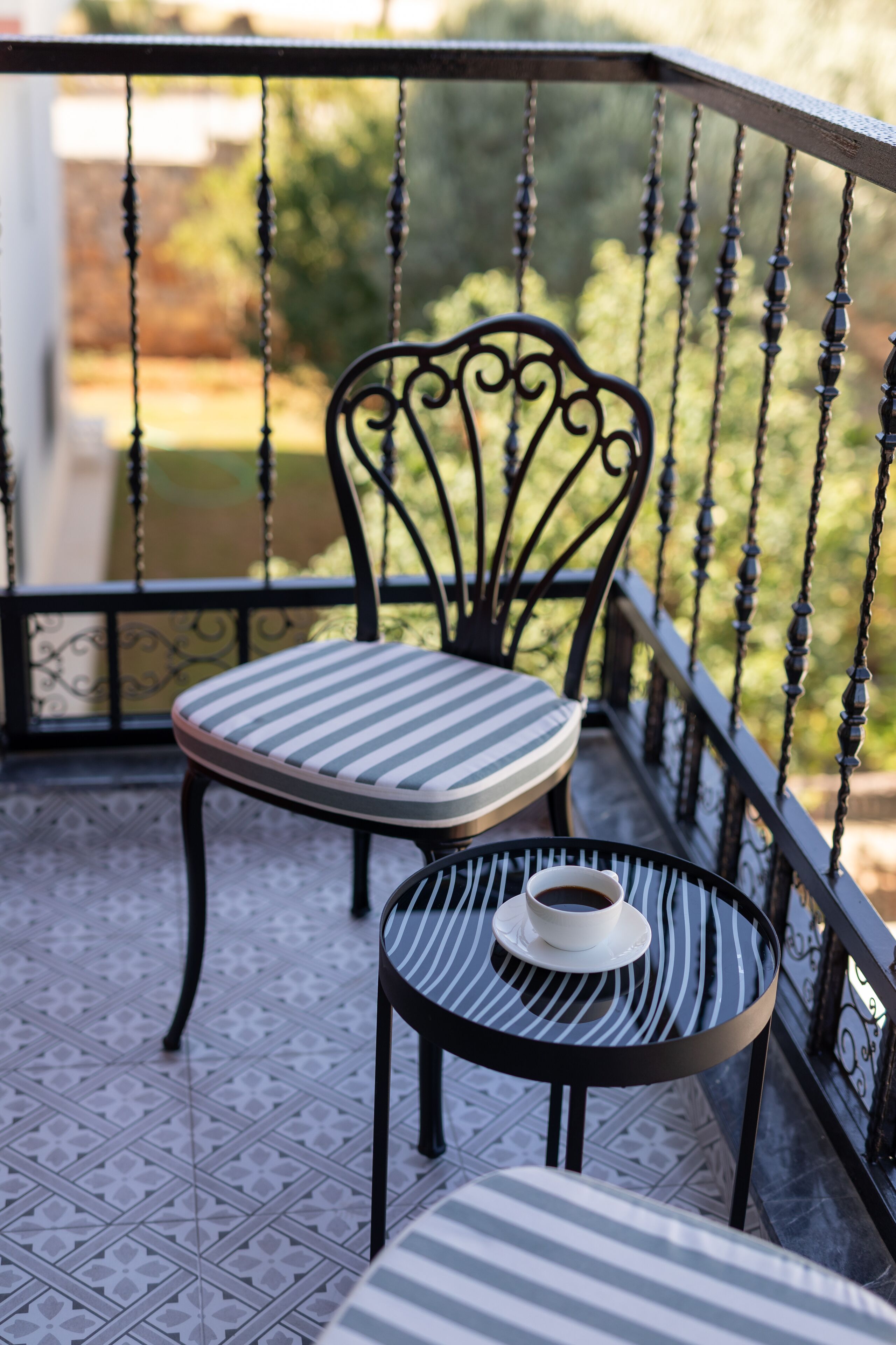 A balcony with a chair and a small table, both with striped cushions.