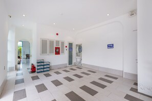 A spacious hallway with a tiled floor, a fire extinguisher, and a fire alarm on the wall. - La Casa Hotel (Ho Chi Minh City)