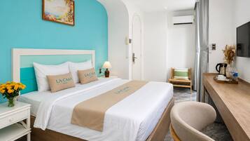 Habitación de hotel con cama, escritorio, silla, televisor y un cuadro en la pared.