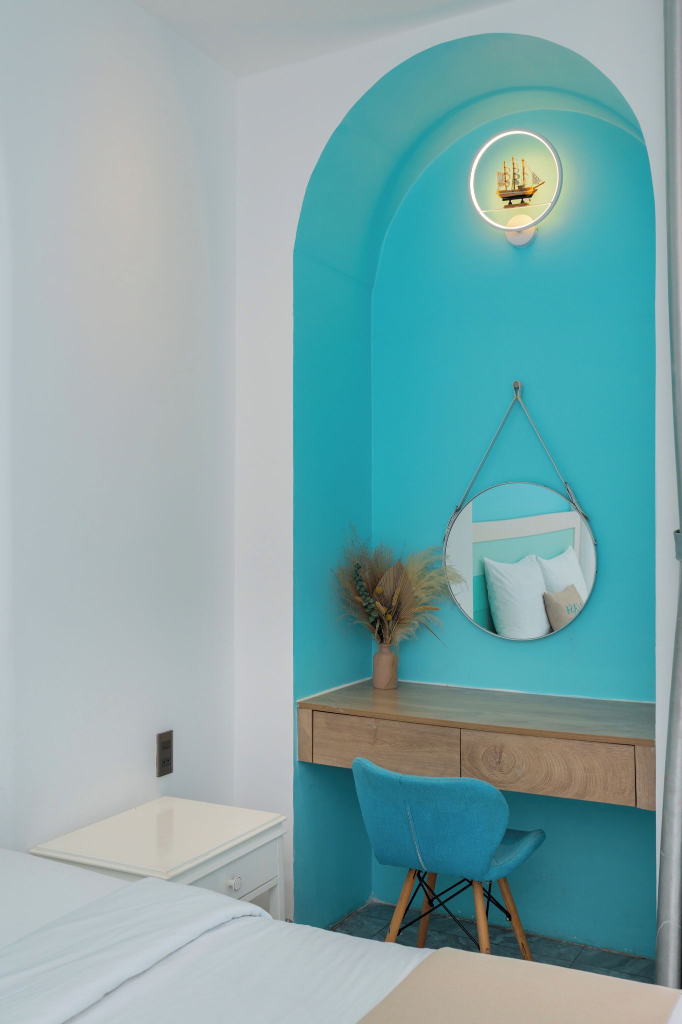 A bedroom with a bed, a desk, and a hanging chair.