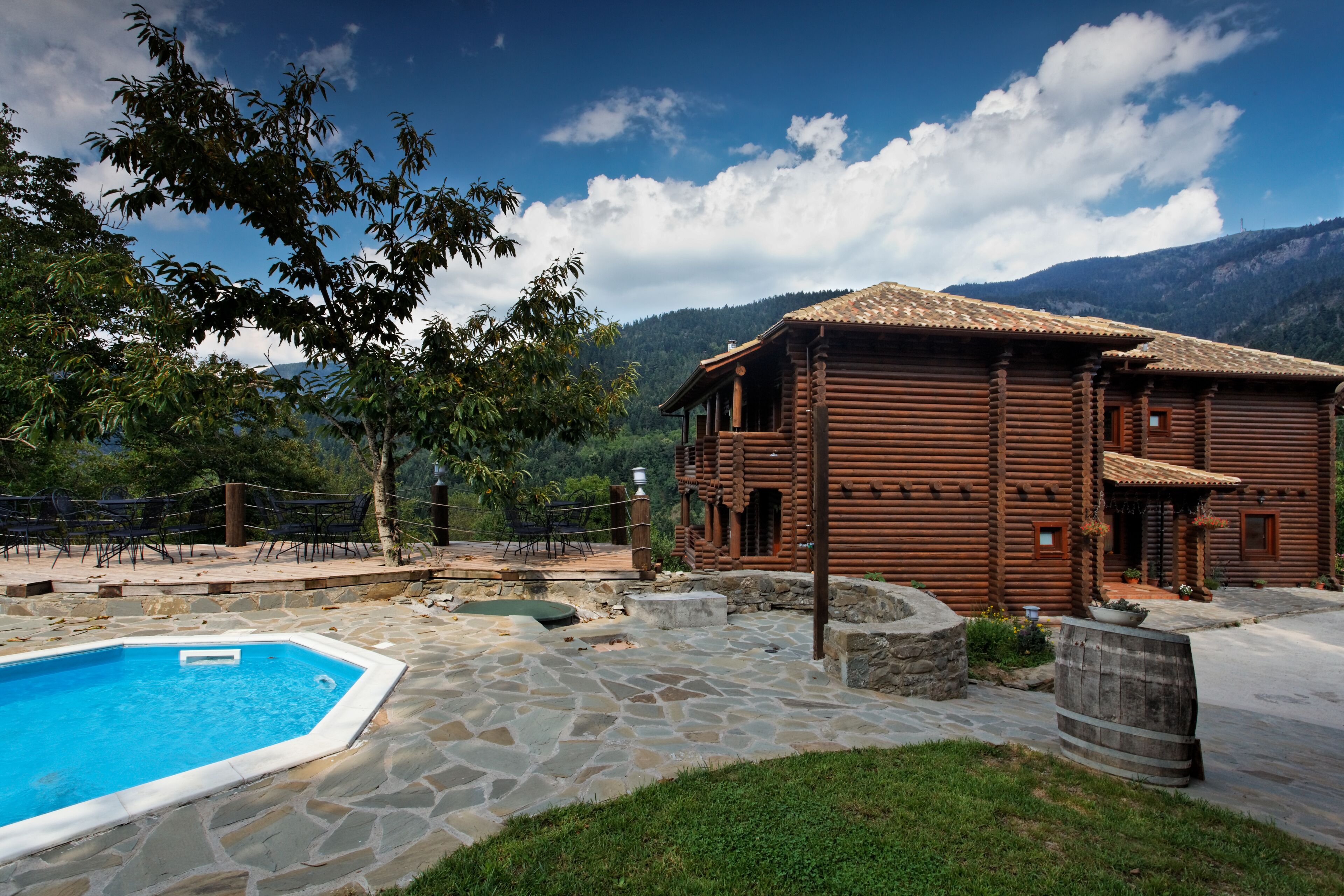 A wooden log cabin with a stone pool and outdoor seating area.
