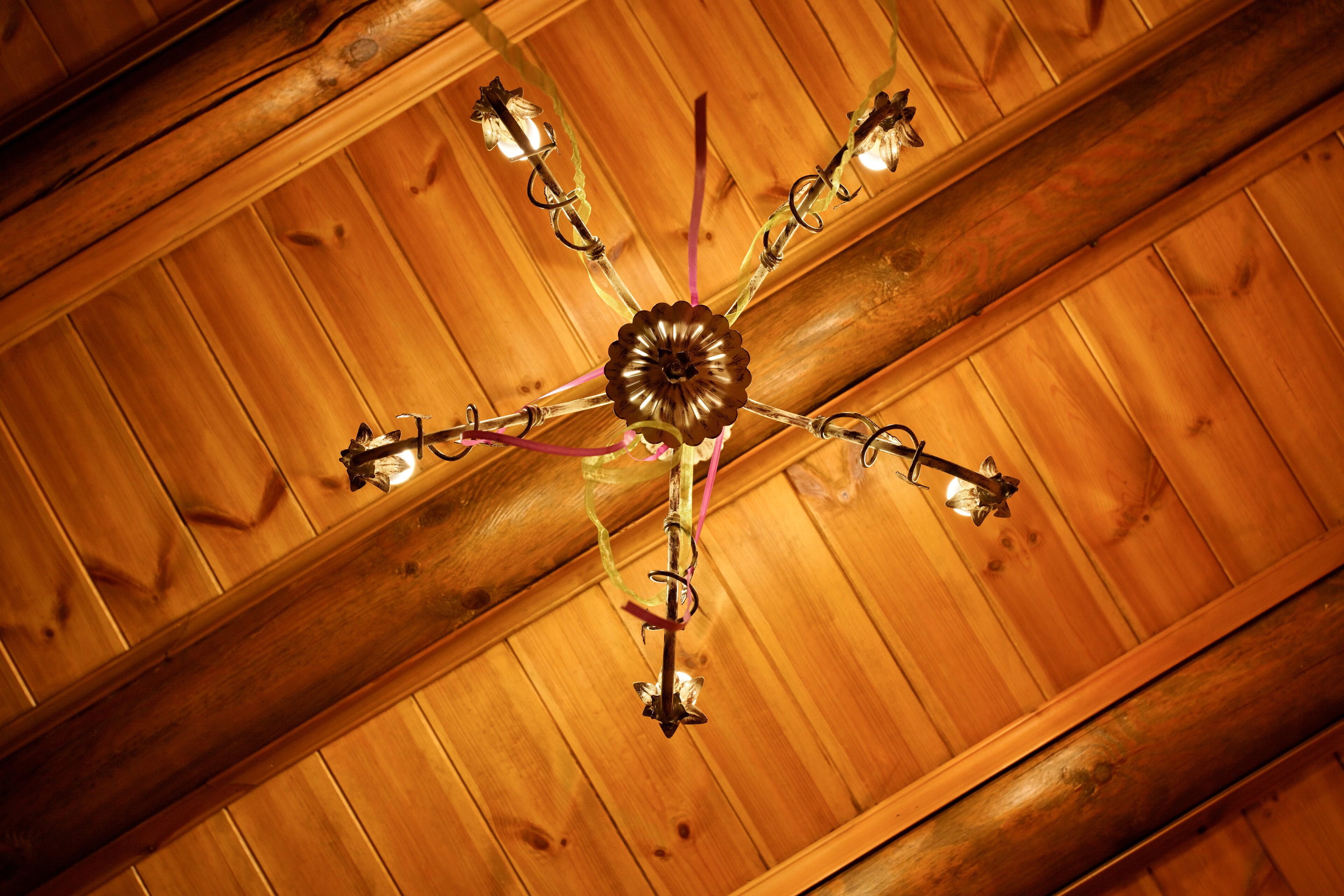A ceiling with a central chandelier and wooden beams.