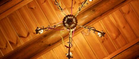 A ceiling with a central chandelier and wooden beams.