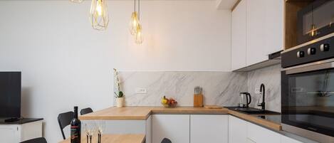 A modern kitchen with a wooden dining table, white cabinets, and a built-in oven.