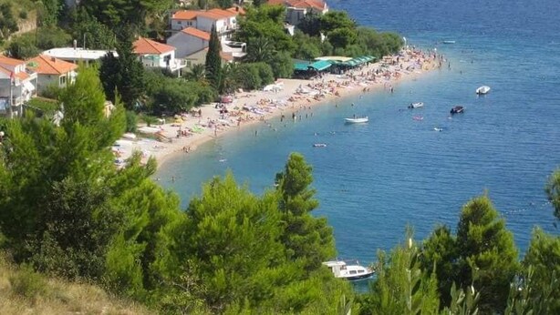 A coastal town with a beach, boats, and buildings. - Apartments Tomas (Omis)