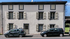 Un bâtiment à deux étages, doté de nombreuses fenêtres et de volets, avec des voitures garées devant.