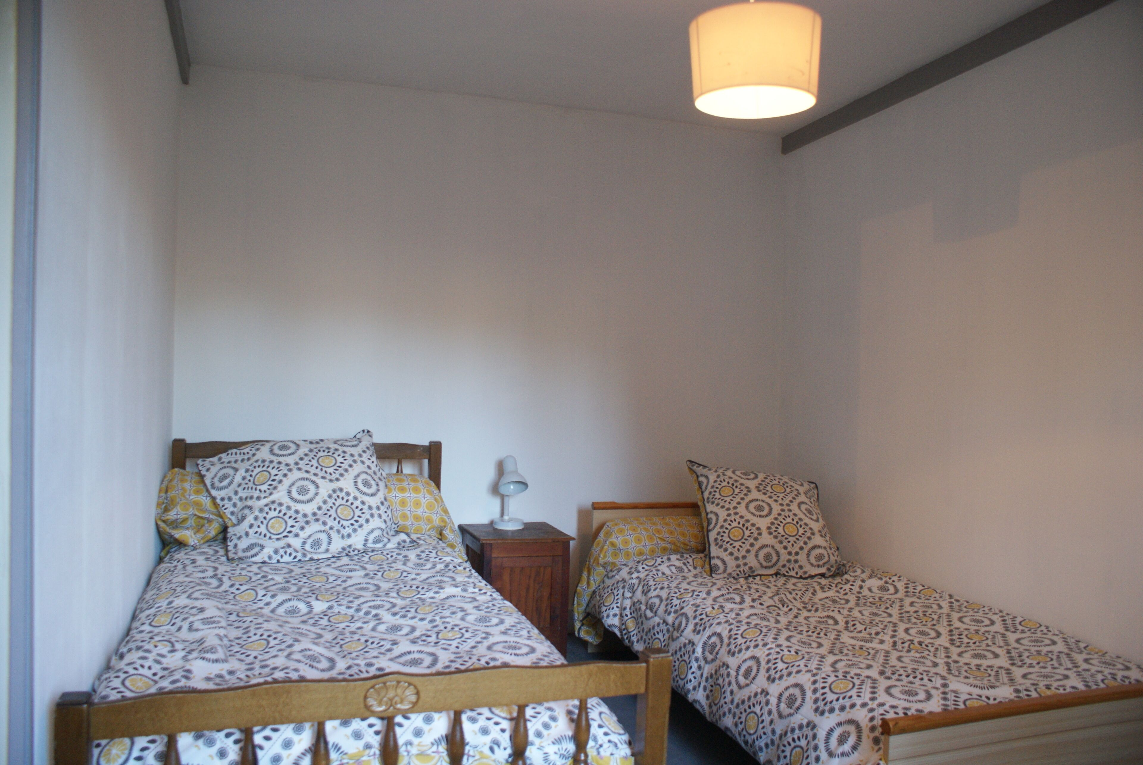 Une chambre avec deux lits simples, chacun agrémenté d’une literie à motifs et d’une table de chevet avec une lampe.