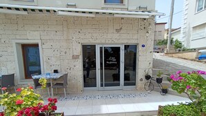 Un edificio con vestíbulo de baldosas, una pequeña mesa con sillas y macetas con flores.