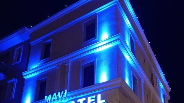 Un hotel llamado "Mavi Liman Otel", con letreros iluminados y fachada de ladrillo.