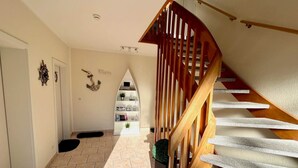 A staircase with wooden railings and a landing area with a white shelf unit.
