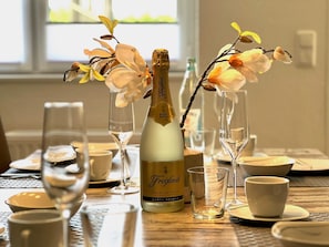 Ein gedeckter Tisch mit einer Freixenet-Champagnerflasche, zwei Blumenvasen und mehreren Weingläsern.