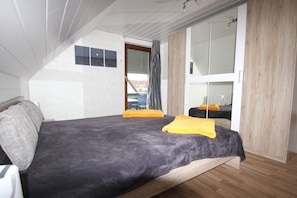 Cozy retreat with a single bed, wooden wardrobe, and a compact seating area.