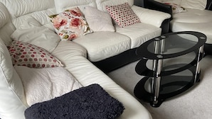 A modern living room with a sectional sofa, a glass coffee table, and a decorative mirror. - Captivating 2-bed House in Wolverhampton (Wolverhampton)