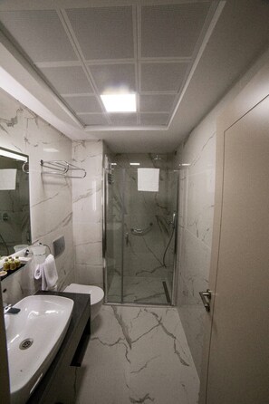 Een moderne badkamer met een grote wastafel, spiegel en douche.