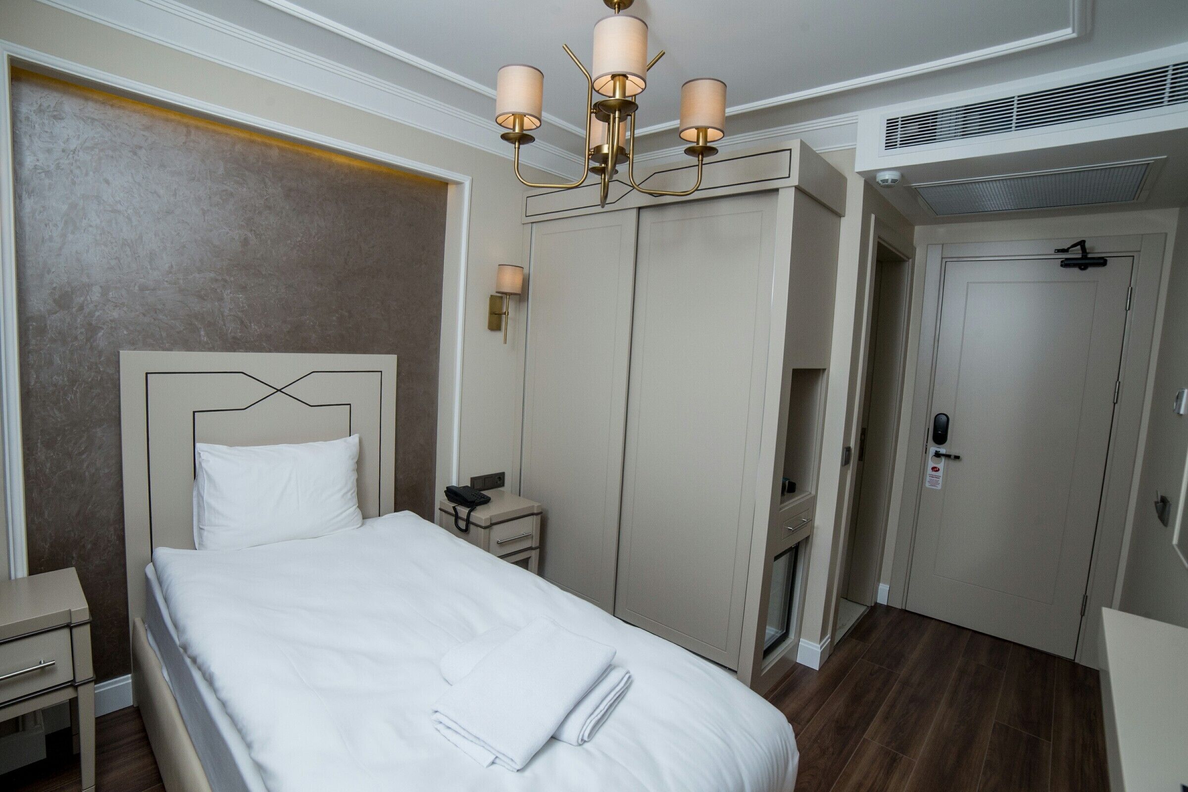 Ein Hotelzimmer mit einem großen Bett, Nachttischen, einem Kleiderschrank und einer Deckenleuchte.