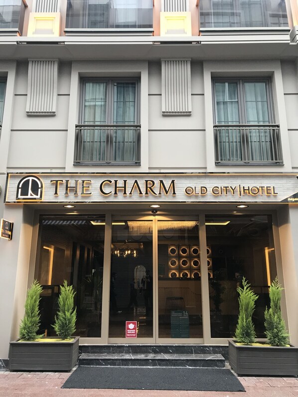 Het uiterlijk van The Charm Old City Hotel met een moderne gevel, grote ramen en een opvallende entree met een kroonluchter.