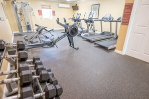 A gym with cardio machines, weight benches, and dumbbells.