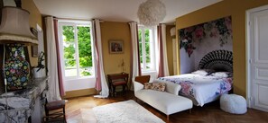 A bedroom with a bed, a sofa, a desk, and a large window.
