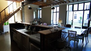 Une cuisine moderne dotée d’un grand îlot central, d’appareils électroménagers en acier inoxydable et d’un coin repas avec une table et des chaises.