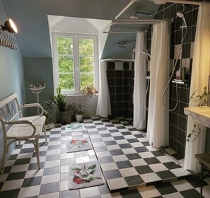 A bathroom with a checkered floor, a shower area, a window with curtains, and a bench.
