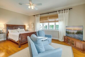 A bedroom with a bed, a sofa, a TV, and a ceiling fan.