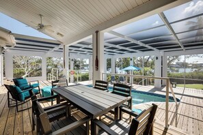 Et overdækket udendørs område med pool, træterrasse og siddepladser.