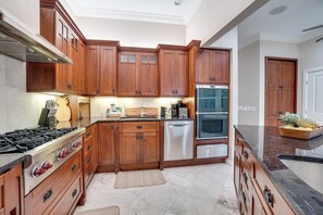 A modern kitchen with wooden cabinets, stainless steel appliances, and a marble countertop.