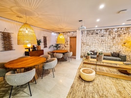 Amplia sala de estar con pared de piedra, mesa de comedor de madera y asientos cómodos.