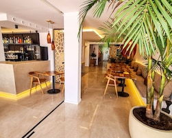 Un área de bar moderna con mostrador, taburetes y un espacio de estar con sofá y una planta en maceta.