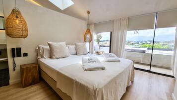 Un dormitorio moderno con una cama grande, un teléfono en la pared y vistas del paisaje por la ventana.