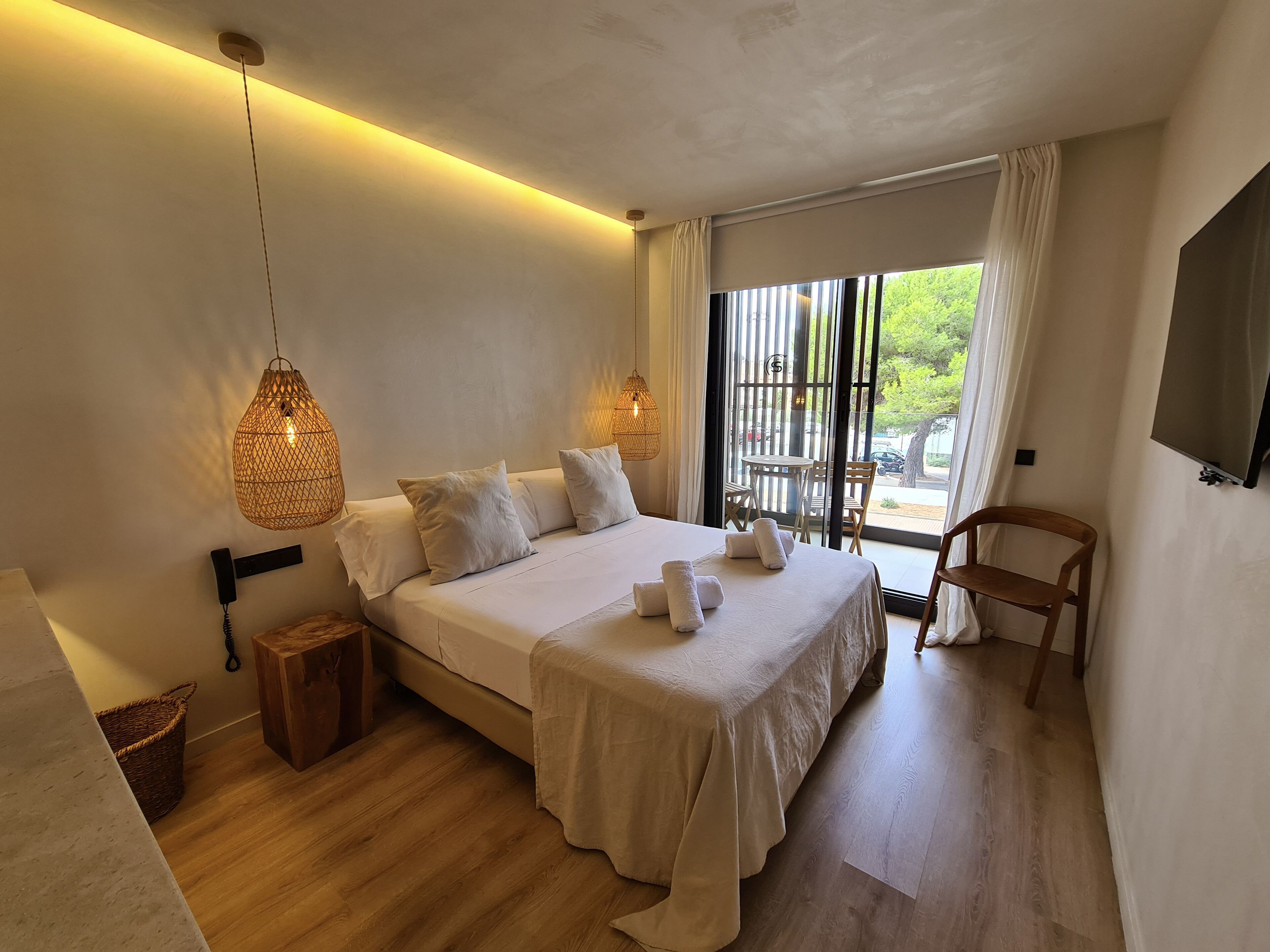 Una camera da letto con un letto grande, lampade sui comodini, pavimento in legno, un tavolino e una sedia.