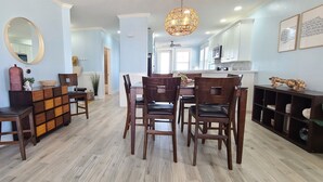 Uma sala de jantar com mesa e cadeiras de madeira, um espelho decorativo e um lustre.