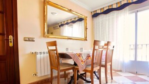 A dining area with a checkered floor, wooden chairs, a table with a red and white tablecloth, a large mirror, and a window with curtains. - Los Mayorales Apartment (Garrovilla, La)