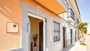 A building with a stone facade, a door with a number '30' above it, and a potted plant inside. - Los Mayorales Apartment (Garrovilla, La)