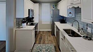 A compact kitchen with white cabinets, a microwave, a toaster, and a sink. - Oceanfront Beach View, Large Pool, Updated! (Pawleys Island)